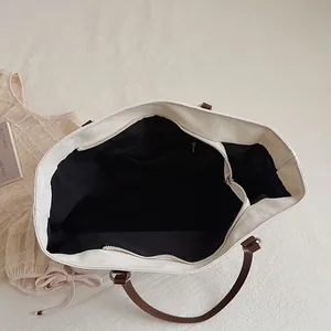 Close-up of canvas tote bag interior with zipper pocket and brown leather handles