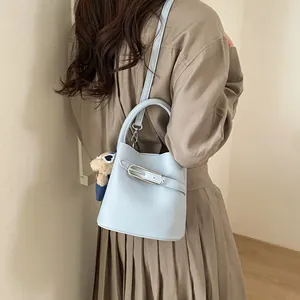 Borsa a secchiello azzurra con pelle testurizzata e ciondolo a orsetto su modella