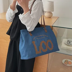 Close-up of blue denim tote bag with leather strap and stylish graphic print