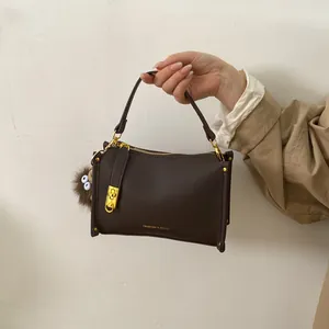 Detail of dark brown lychee texture tote with gold hardware and plush charm on trench coat