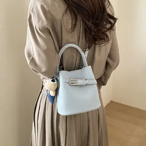 Dettaglio della borsa a secchiello azzurra in pelle con fibbia argento e orsetto