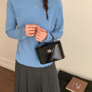 Detail einer schwarzen glänzenden quadratischen Handtasche mit silbernem Metalldrehverschluss