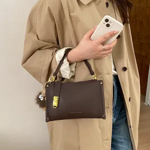 Detail of vintage coffee leather Boston bag with gold twist lock and cute plush charm