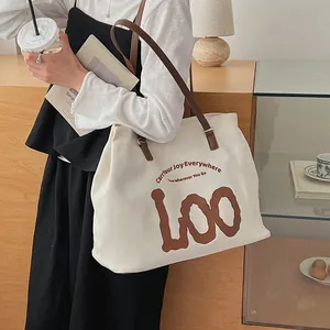 Minimalist beige canvas tote bag with brown leather straps and artistic typography print