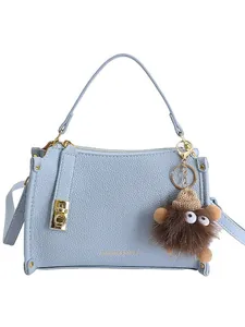 Light blue faux leather Boston bag with gold hardware and a brown furry monster charm