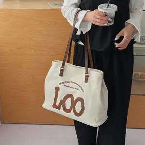 Detail of canvas tote bag featuring brown artistic LOO print and motivational slogans