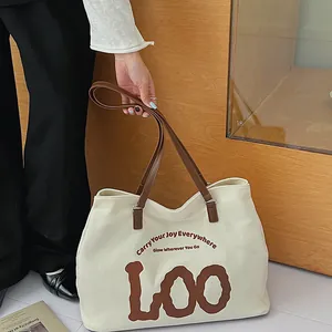 Detail of minimalist cream canvas tote bag with brown straps and large LOO print