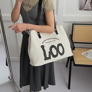 Detail view of large white canvas tote bag with black leather straps and Joy slogan print
