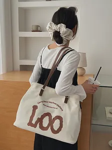 Minimalist off-white canvas tote bag with brown leather straps and artistic lettering