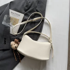 Détail du sac à main en cuir crème avec un charmant pendentif d'ours en peluche