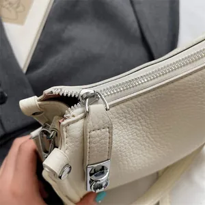 Detailed close-up of cream leather texture and silver zipper on a vintage handbag