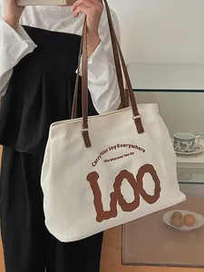 Chic off-white canvas tote bag with brown leather straps and artistic lettering print