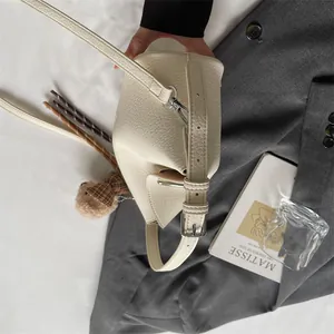 Détail du sac blanc cassé en cuir grainé avec boucles argentées et pendentif d'ours
