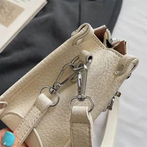 Macro detail of beige lychee grain leather with silver metal hardware and zipper