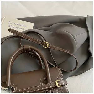 Detail view of dark brown leather handbag featuring contrast stitching and gold hardware