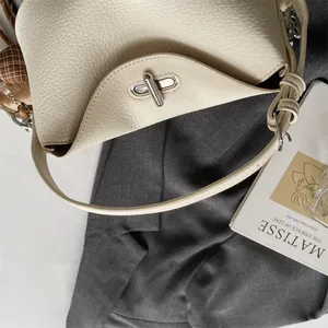 Détail du sac en cuir grainé crème avec fermoir rotatif argenté et finitions de couture
