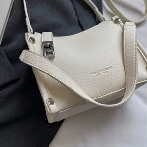 Close-up of litchi textured leather on beige handbag with silver buckle and rivets