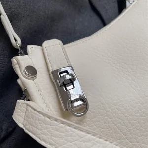 Close-up of white lychee texture faux leather bag with silver metal twist lock and stud