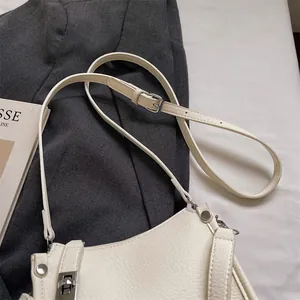 Macro detail of creamy white lychee grain leather crossbody bag with silver hardware