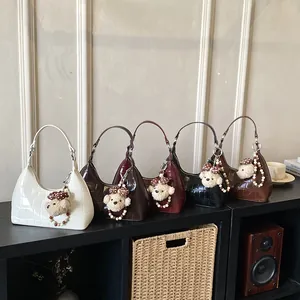Détail de sacs à bandoulière tendance effet crocodile en cinq couleurs avec breloques