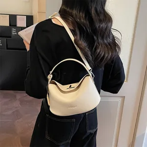 Sac à main chic en cuir grainé blanc cassé avec bandoulière réglable dans un décor minimaliste