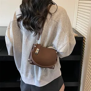 Rear view of model wearing a brown lychee pattern crossbody bag with silver hardware
