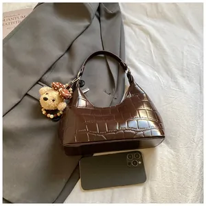 Détail du sac hobo avec texture crocodile, boucles en métal et charm d'ours en peluche
