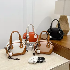 Detailansicht von vier Boston-Mini-Handtaschen mit Baseball-Anhängern auf Steintischplatte