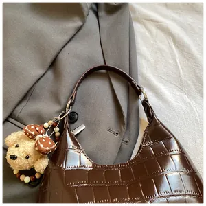 Détail du sac à épaule marron texture crocodile avec un pendentif ours en peluche mignon