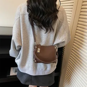 Detail of vintage chocolate brown leather crossbody bag with silver buckle and rivets