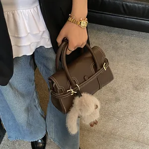 Detail of dark brown vintage handbag with contrast white stitching and cute rabbit charm