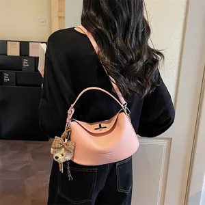 Gros plan détaillé du sac en cuir rose grainé avec fermoir rotatif et breloque petit ours