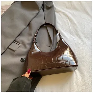 Détail de la texture crocodile marron foncé sur un sac à bandoulière vintage en demi-lune