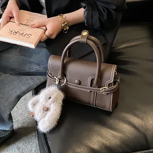 Close-up of vintage brown leather handbag with contrast stitching and plush rabbit charm
