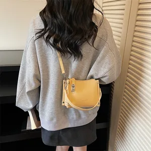 Close-up of yellow lychee grain leather crossbody bag with silver buckles and zipper