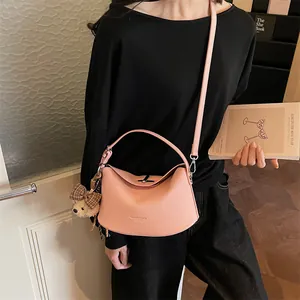 Détail du sac à main rose texture litchi avec poignée et breloque ours mignon