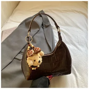 Détail du sac hobo marron foncé effet crocodile avec un joli petit ours en peluche