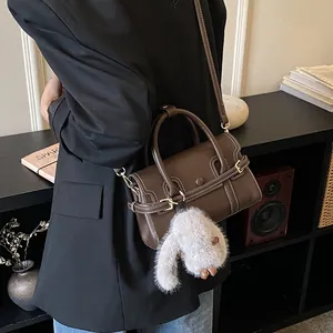 Detail of brown faux leather handbag featuring white contrast stitching and bunny charm