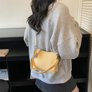 Detail showing the pebbled leather texture and silver hardware of the yellow crossbody bag
