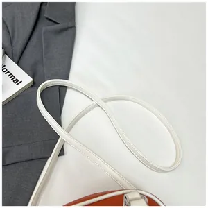 Nahaufnahme der rotbraunen Bowlingtasche aus Leder mit weiß besticktem Riemen auf Blazer