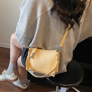 Close-up of yellow lychee texture crossbody bag with silver hardware on a model