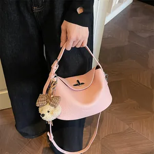 Gros plan d'un sac à main en cuir rose avec motif litchi et breloque ours en peluche