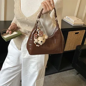 Détail du sac hobo marron à motif crocodile avec un joli pendentif ours en peluche