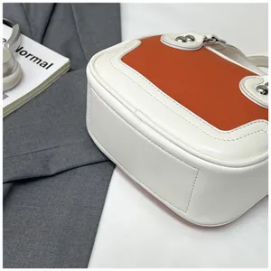 Details der Kontrastnähte und Silbernieten auf einer weiß-braunen Lederhandtasche
