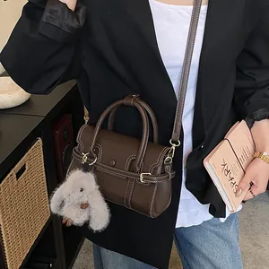Detail showing vintage dark brown leather bag with contrast stitching and rabbit charm