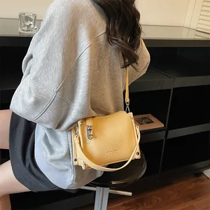 Detail of light yellow lychee pattern leather bag with silver metal hook and rivet accents