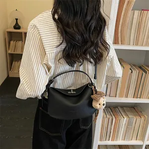 Détail du sac à main en cuir grainé noir avec fermoir argenté et breloque petit ours