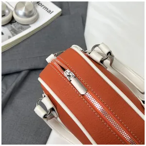 Detailaufnahme der orangefarbenen Bowlingtasche aus Leder mit weißem Rand und Silberreißverschluss