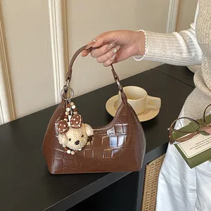 Détail du sac à bandoulière marron effet croco avec un adorable ours en peluche