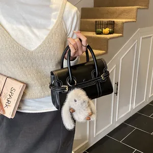 Detail of black handbag with white contrast stitching and cute plush rabbit charm